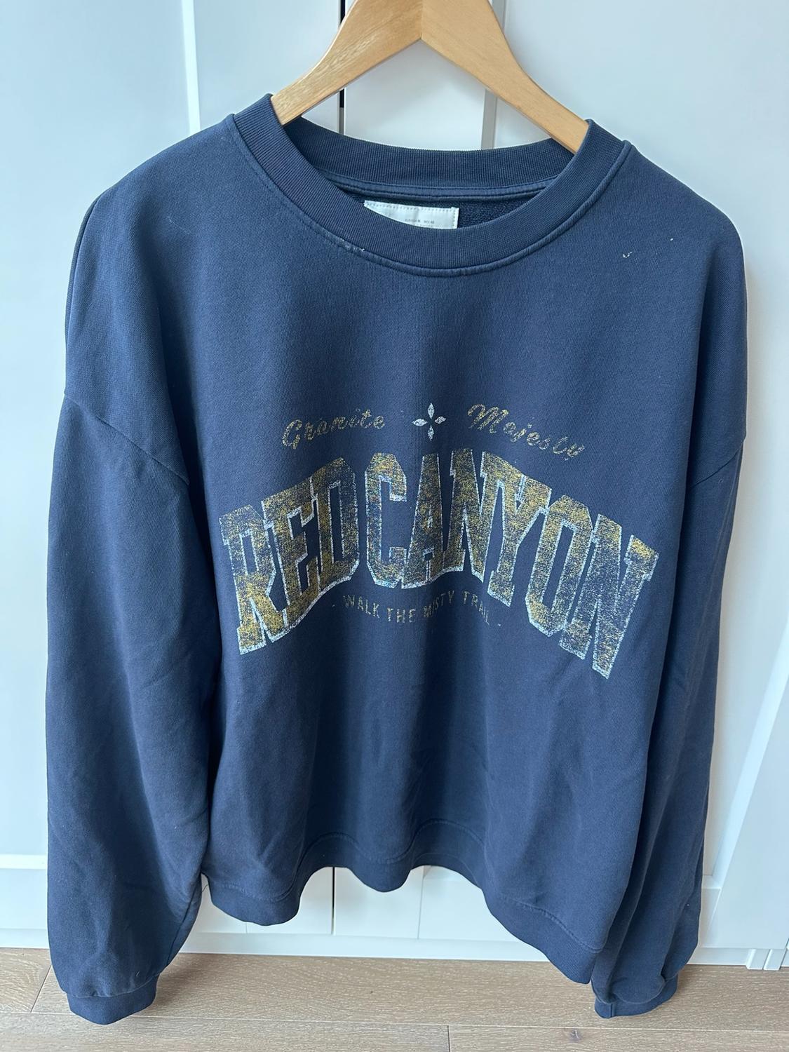 Navy blue casual sweatshirt hanging on a wooden hanger. Front print with text: Granite Majesty, RED CANYON, - WALK THE MISTY TRAIL -.