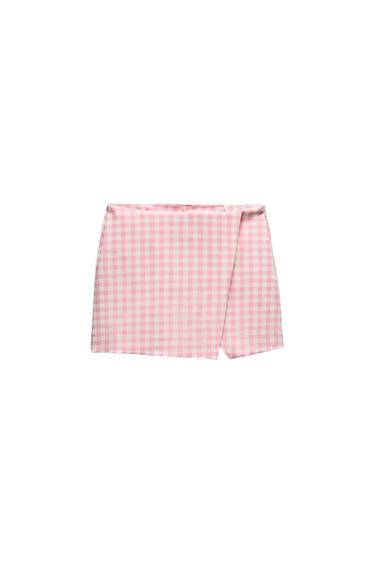 Short gingham skirt in pink and white tones, with a crossover design, on a white background.