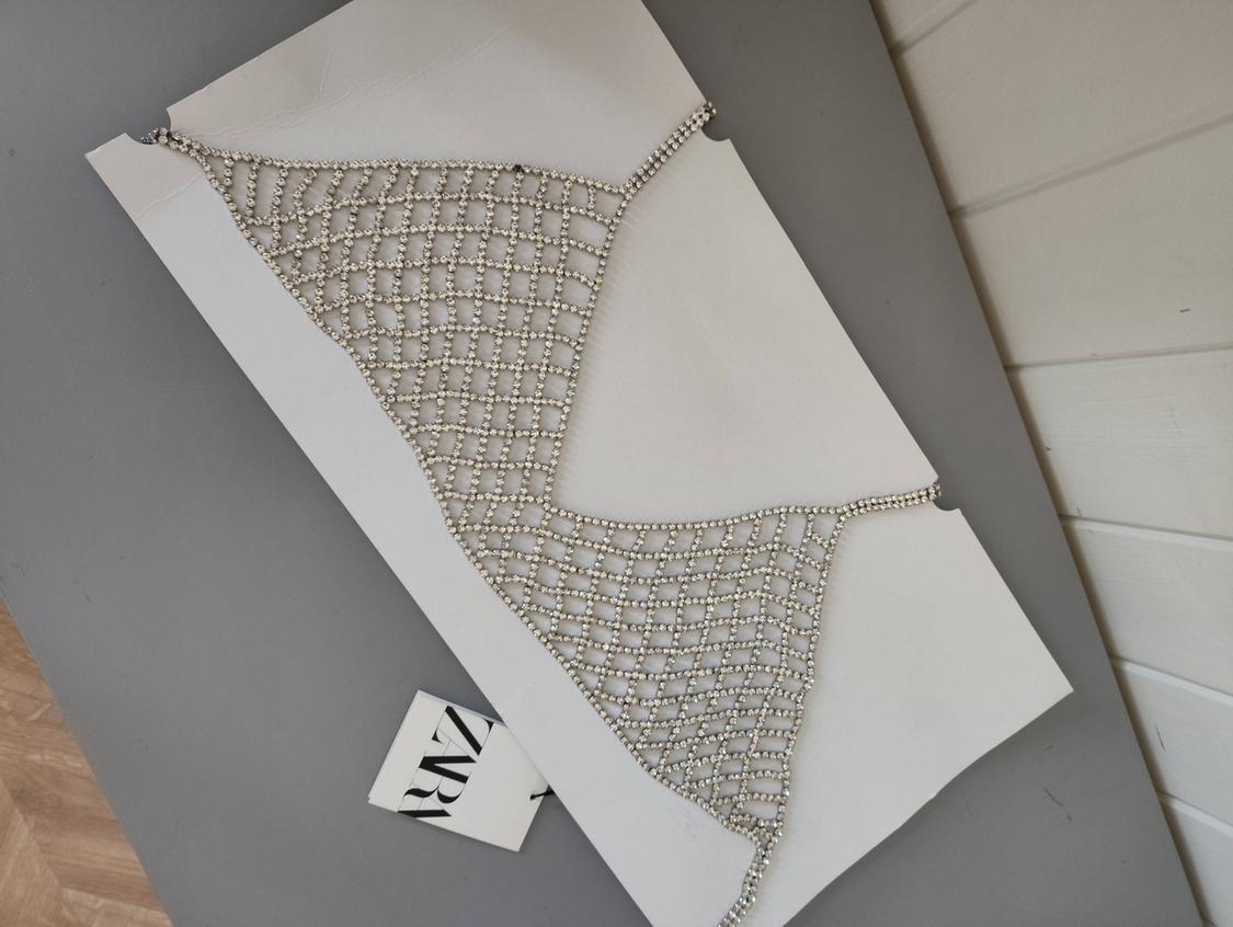 Silver glitter mesh top on a white cardboard backing on a grey surface. Includes a label with the text ZARA.