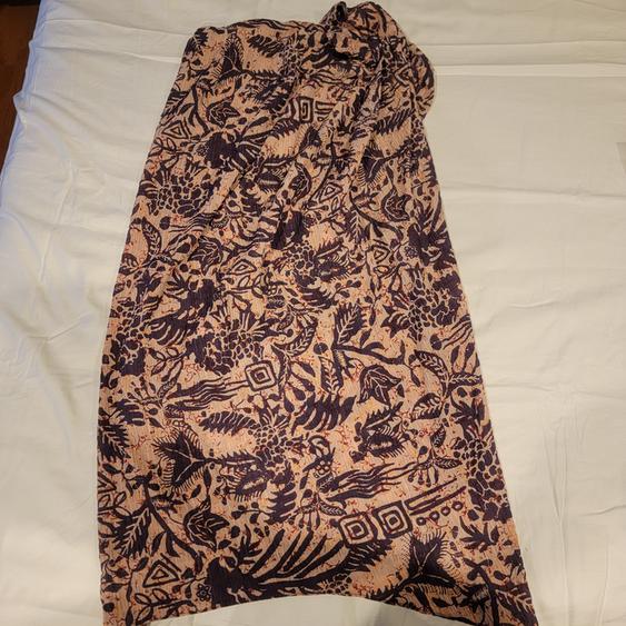 Printed fabric with a floral and geometric design in dark tones on a light background, spread over a white surface.