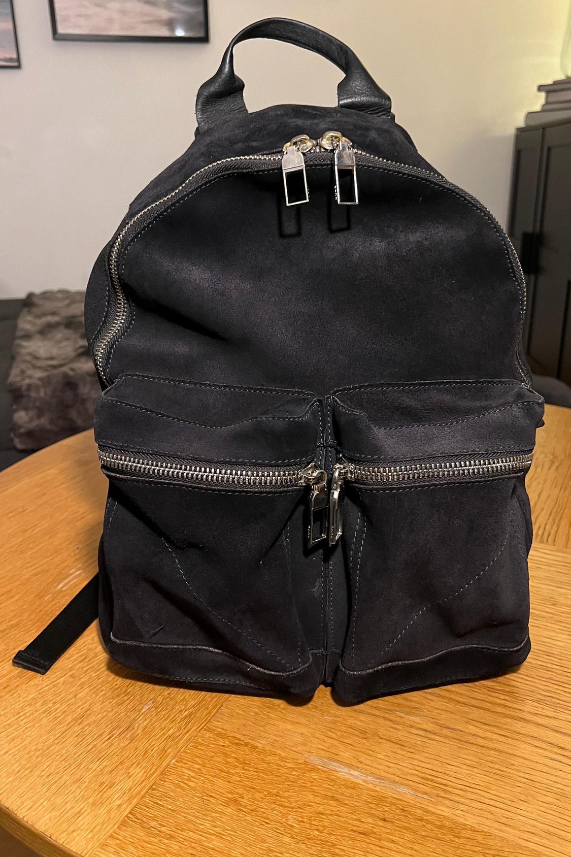 Front view of a black rucksack with two front pockets with zips.