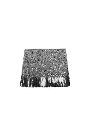Silver mini skirt with sequins and fringe on the bottom, on a white background. Bright and festive design.