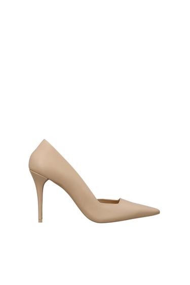 Beige high-heeled shoe with a pointed toe, on a white background. Elegant and minimalist design.