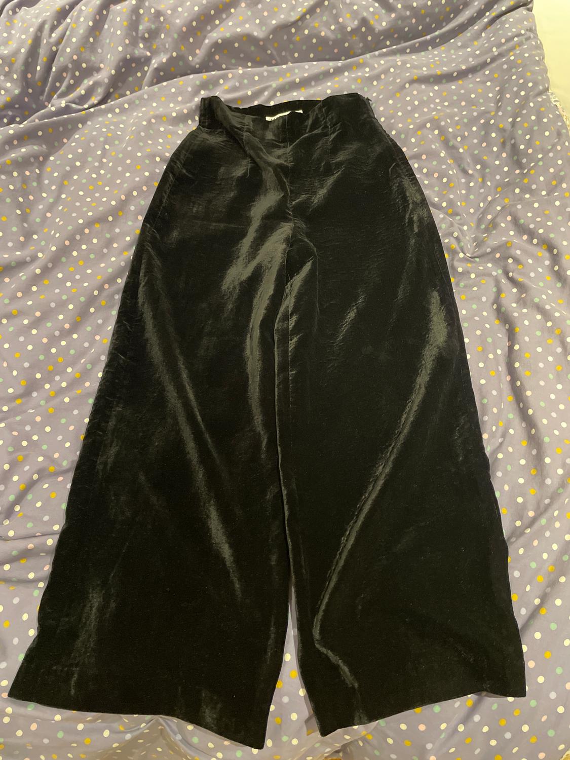 Black velvet trousers on a purple bedspread with white and yellow dots.