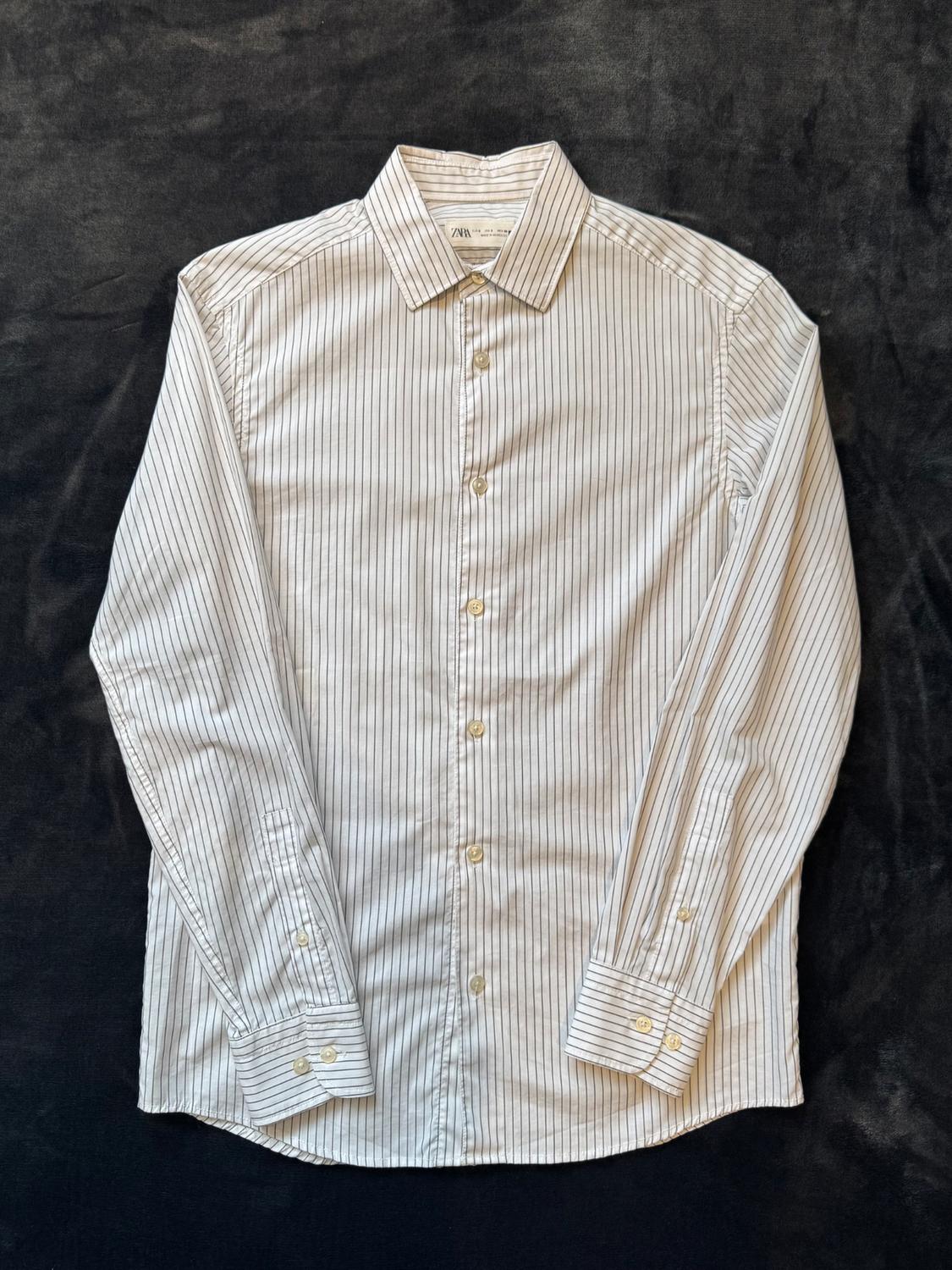 Black and white vertical striped button-down shirt, on a black background. Label visible on the collar.
