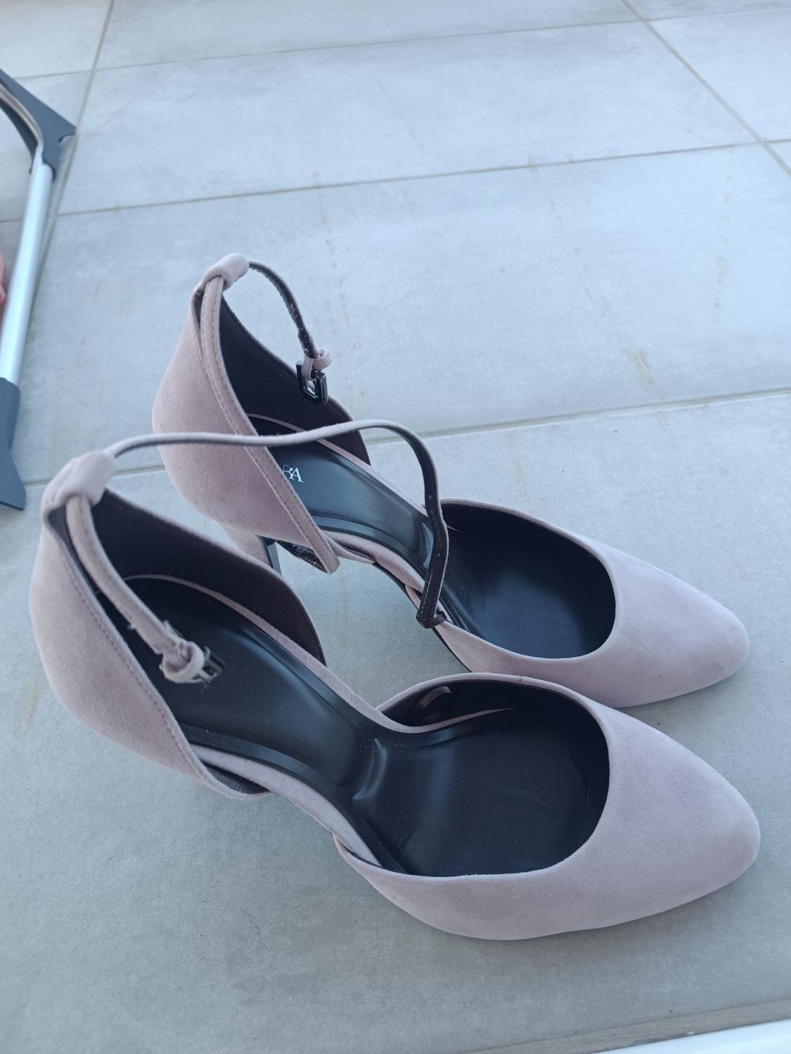 High heels in light pink with thin straps, on a grey tiled floor.