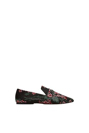 Black flat loafer-style shoe with pink and green floral motifs,
pointed toe, on a white background.