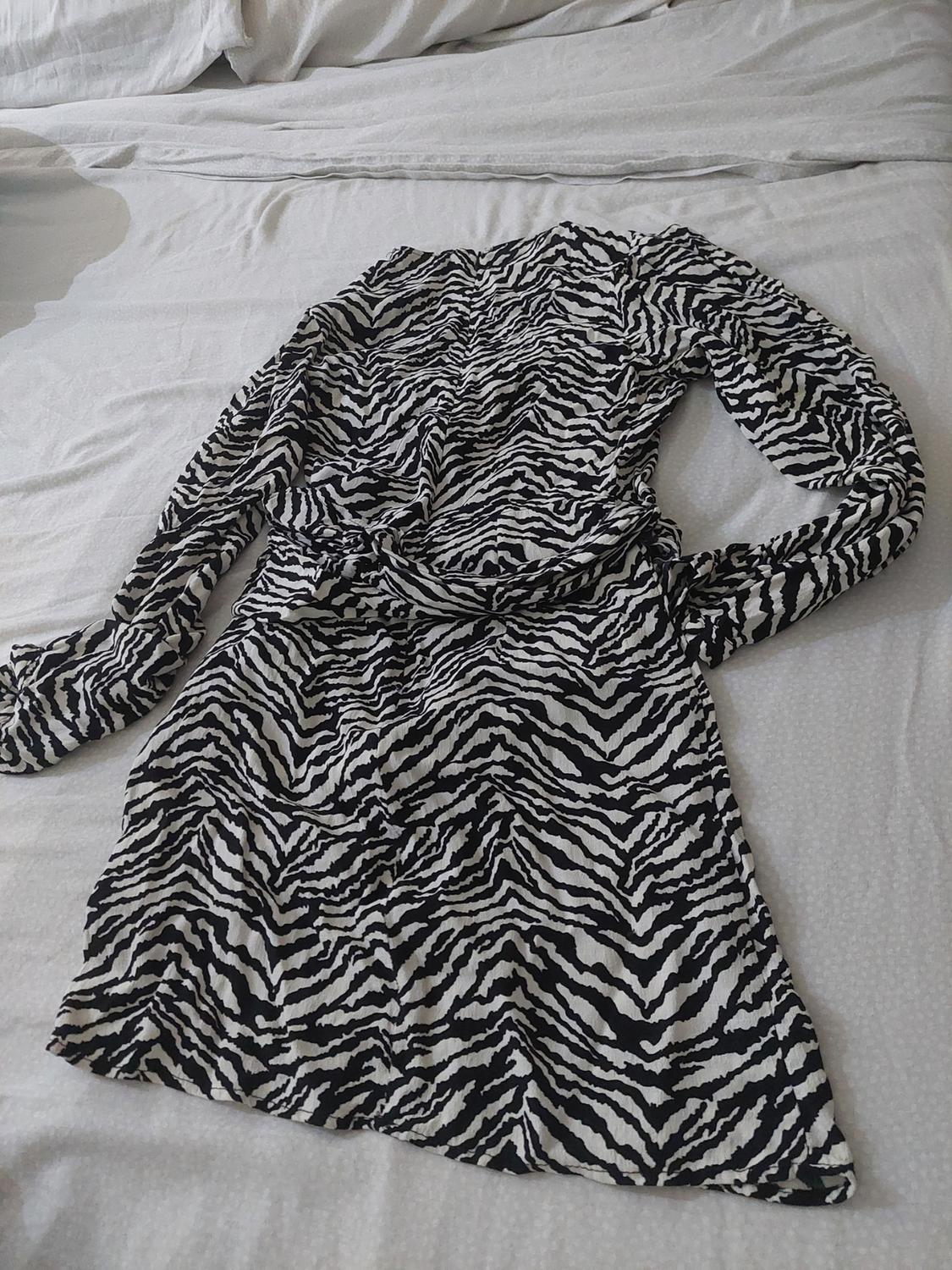 Black and white zebra-print long-sleeved short dress, laid out on a white sheet.