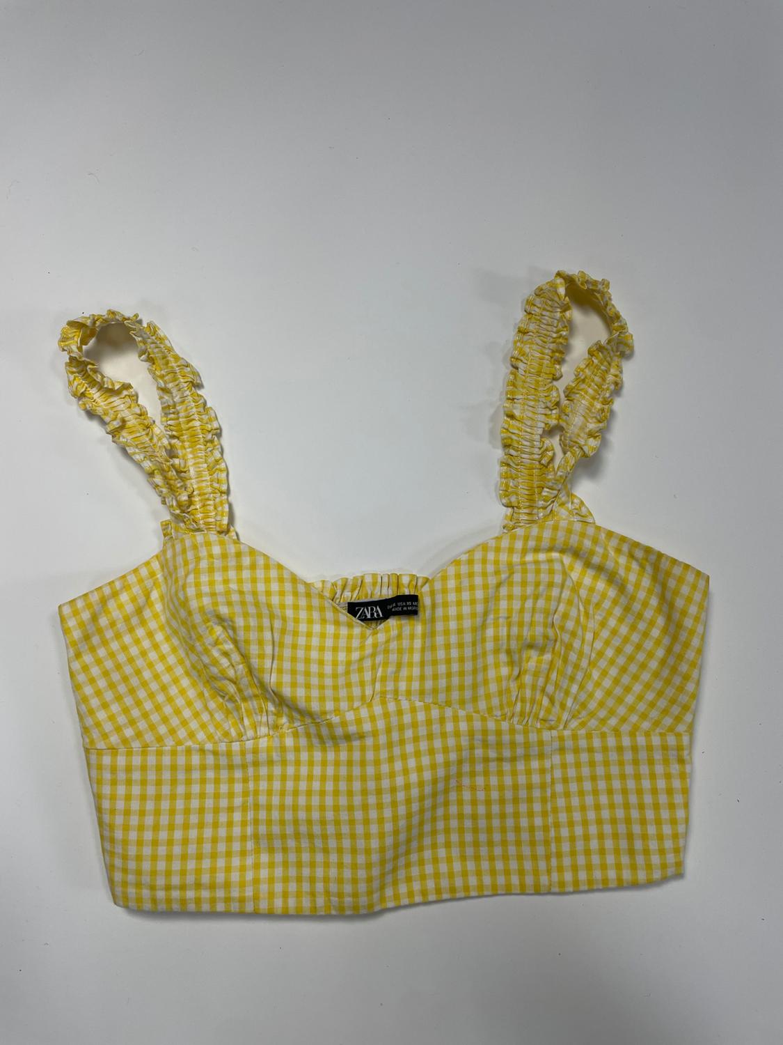 Cropped gingham top in yellow and white with gathered straps against a white background. Visible ZARA label.