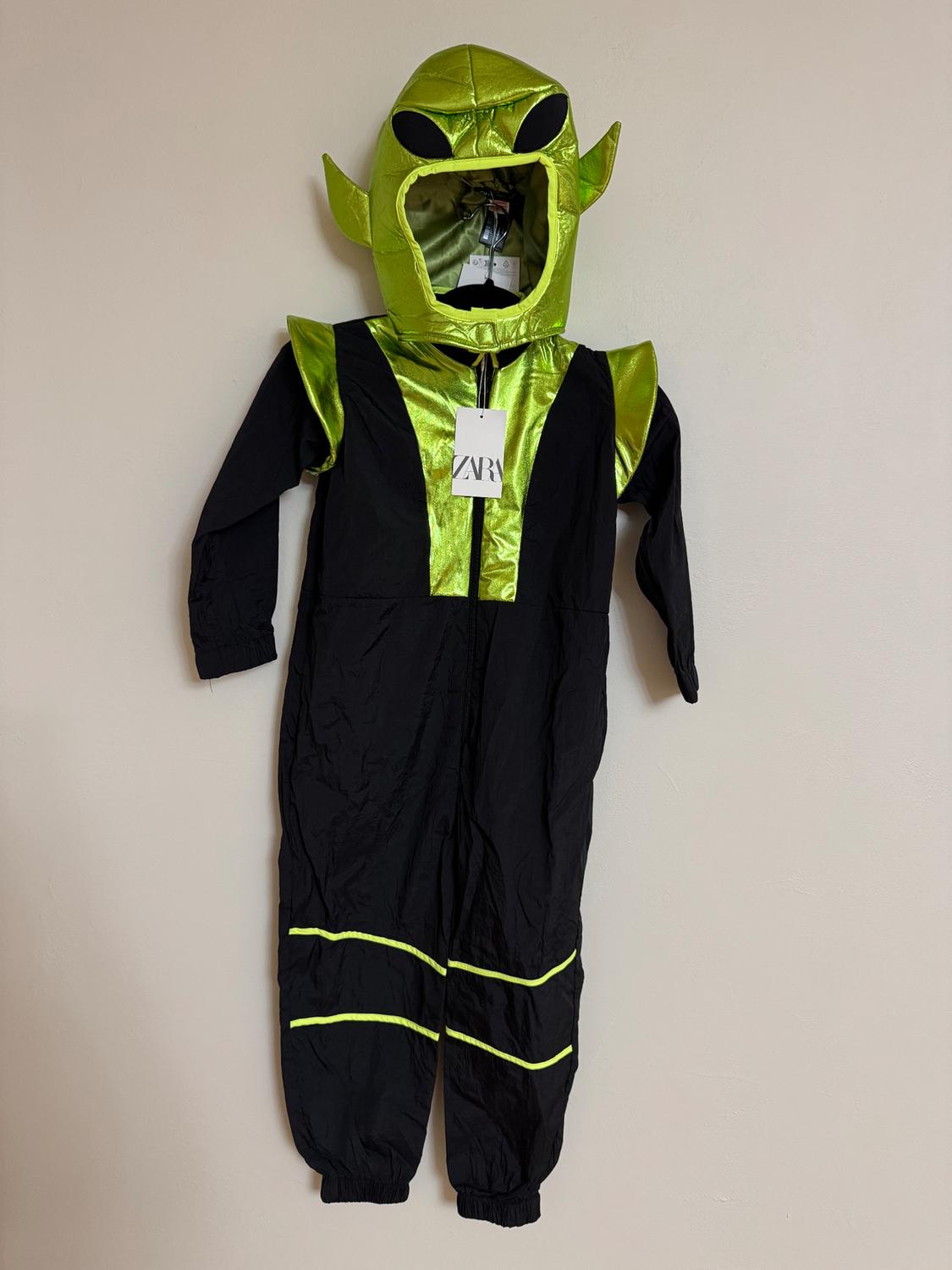 Kids' alien costume in black and bright green with a hood and pointed ears. Visible tag with "ZARA" text.
