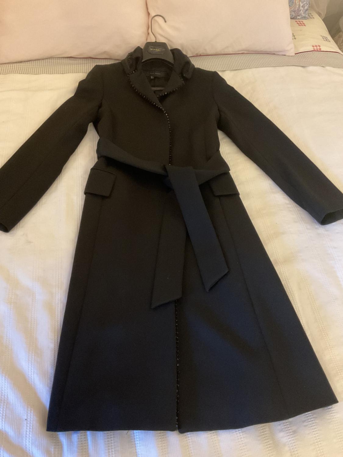 Front view of a black coat with a belt and front flap pockets.