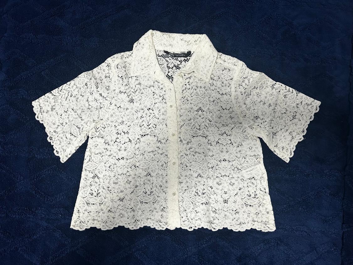 White lace shirt with short sleeves and a classic collar, on a dark blue background.