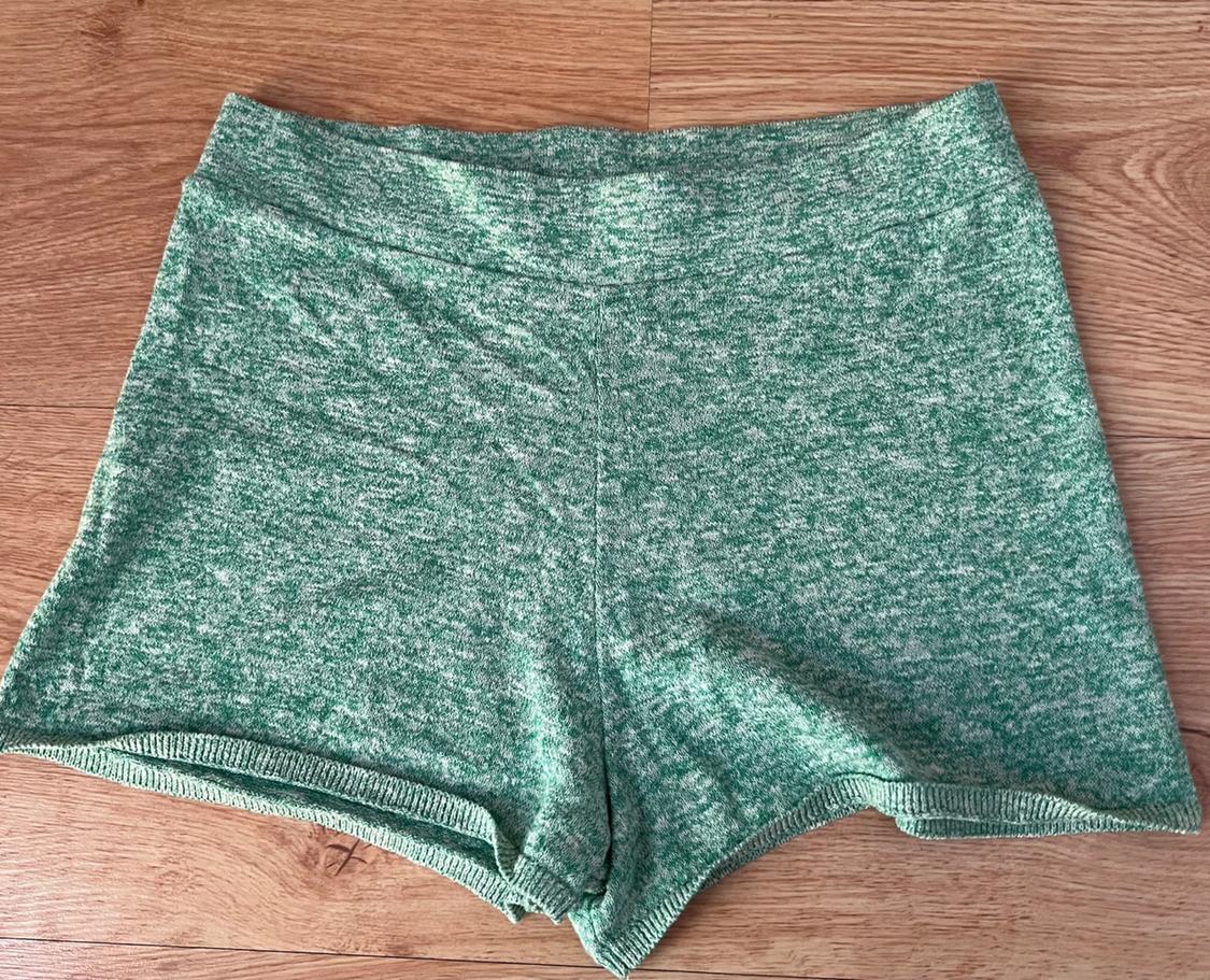 Casual green and white marl knit shorts, relaxed fit, laid out on a wooden floor.