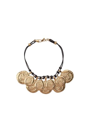 Necklace with gold coin pendants and black cord on a white background. Elegant and striking design.