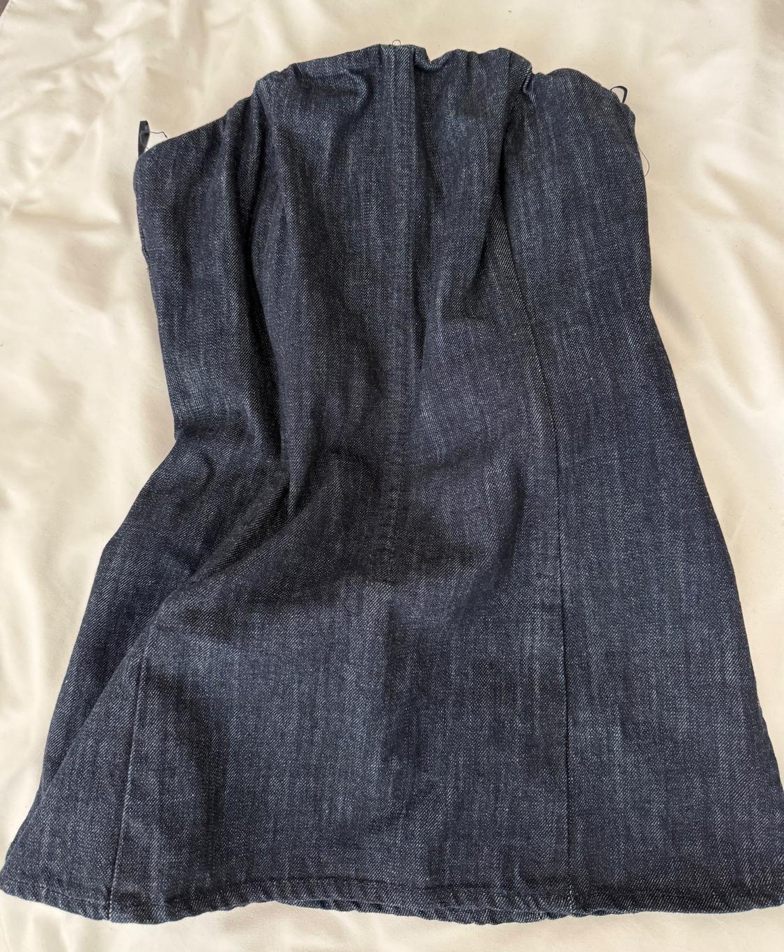 Dark blue denim fabric on a white surface, showing natural texture and folds in the material.
