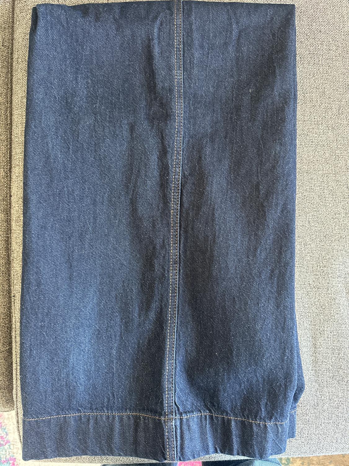 Dark blue denim fabric folded on a grey surface, showing visible seams and material texture.