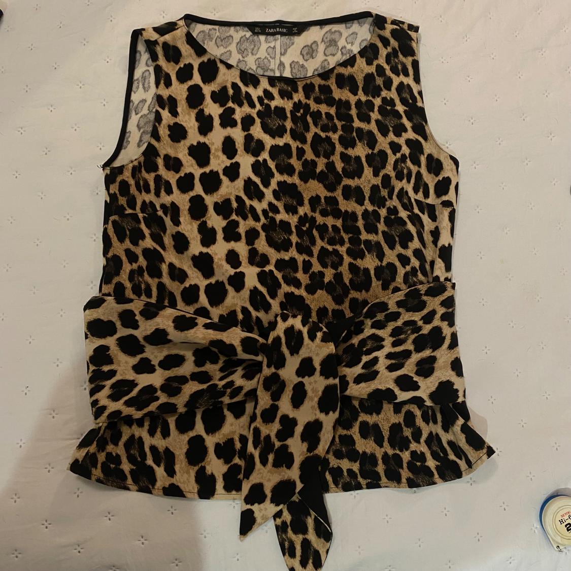 Sleeveless blouse with leopard print and waist tie on a white background. Visible label: "Zara Basic".
