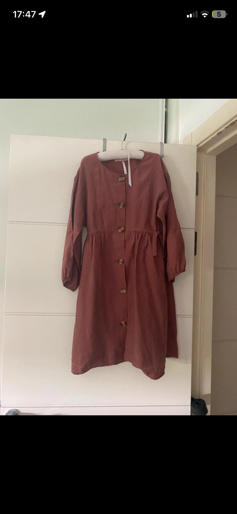 Dark pink long-sleeved dress with front buttons, hanging on a hanger on a white door. Text: 17:47 5.