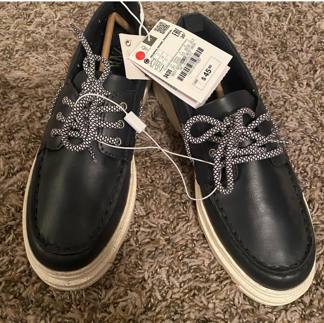 Front view of black shoes with white laces and a white sole.