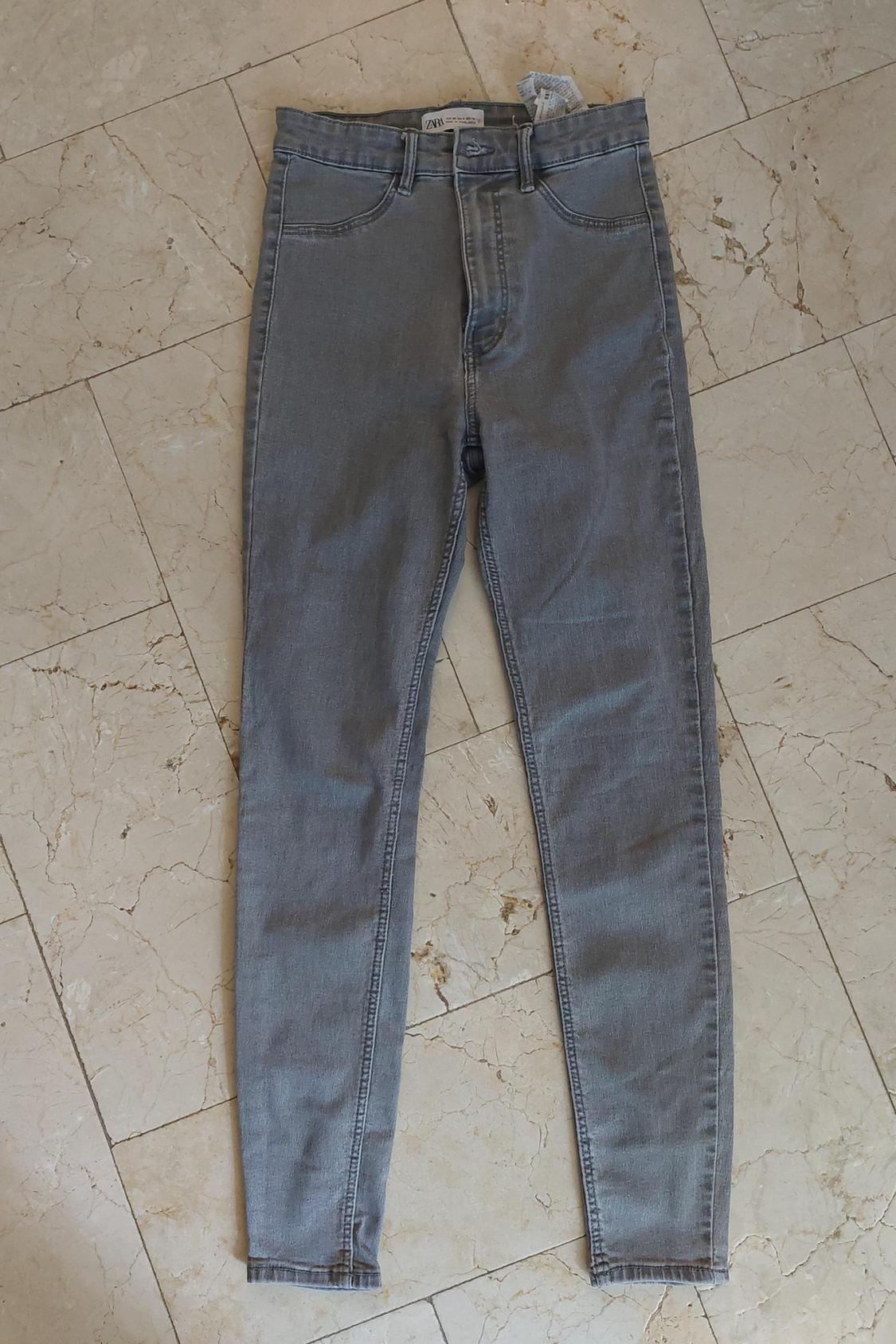 Front view of grey denim jeans with front pockets and belt loops.