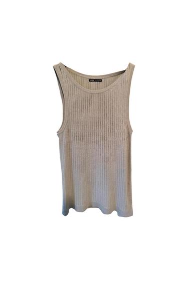 Beige knitted tank top with openwork design, hanging on a white background. Label visible at the neck.