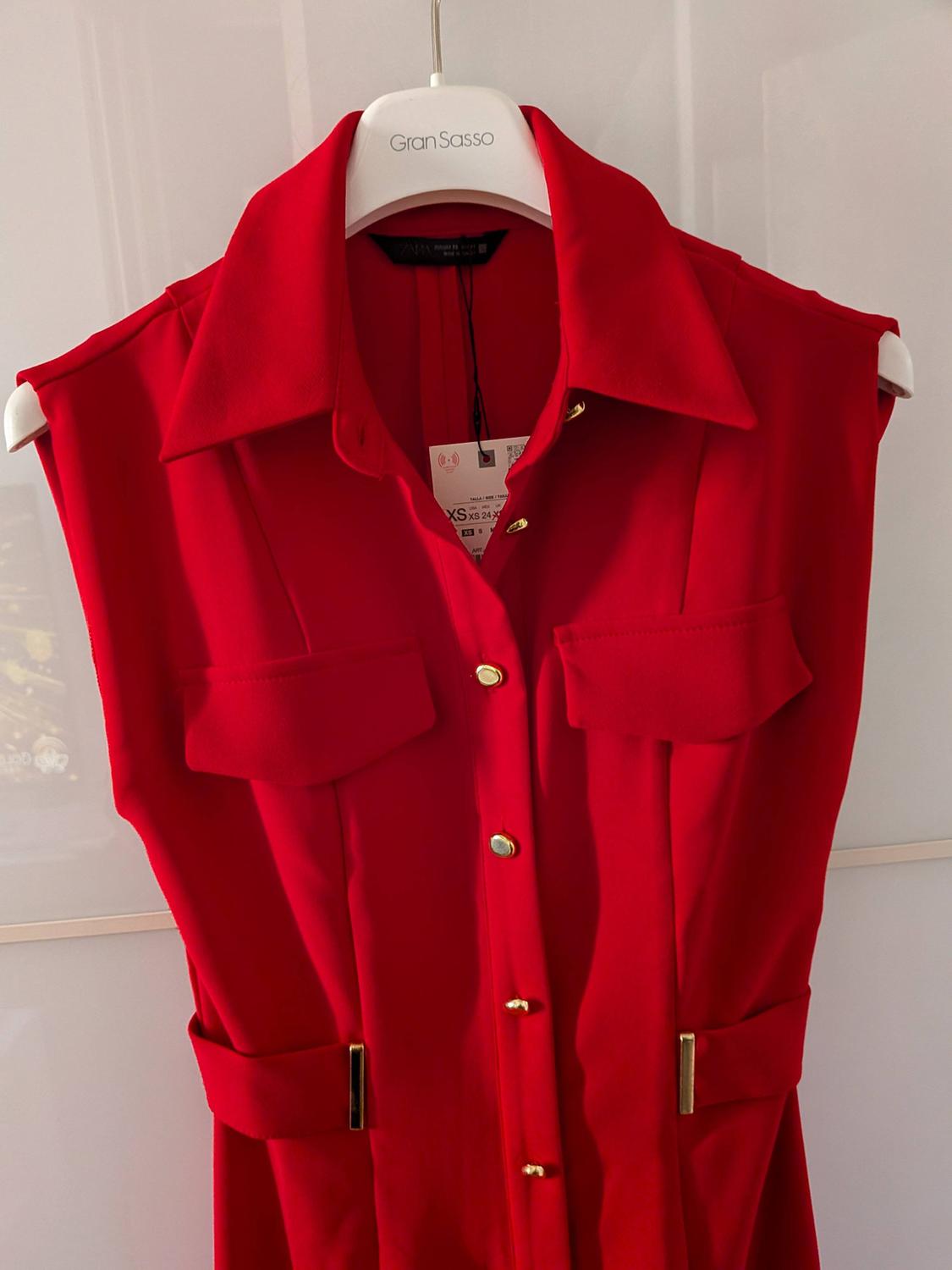 Sleeveless red dress with gold buttons and chest pockets, hanging on a white hanger with the "Gran Sasso" brand.