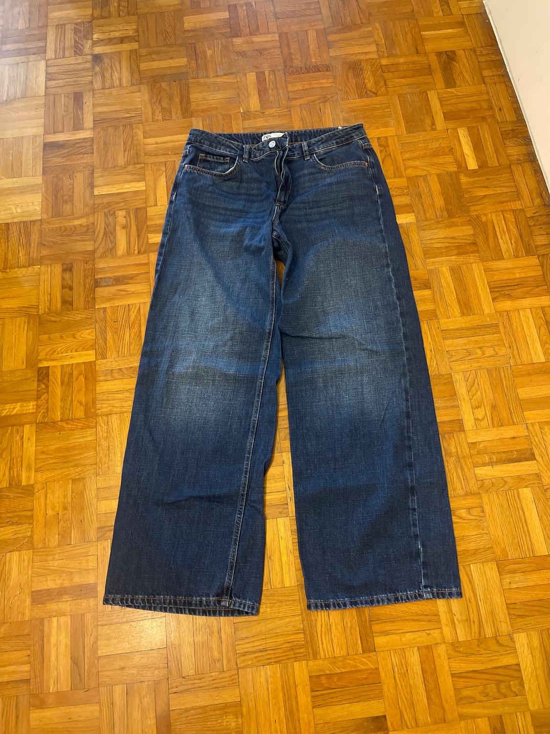 Wide-leg jeans on a parquet floor. They have a classic design with front and back pockets.