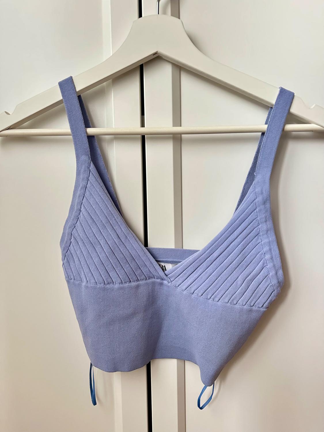 Lilac ribbed cami top on a white hanger in front of a white wardrobe.