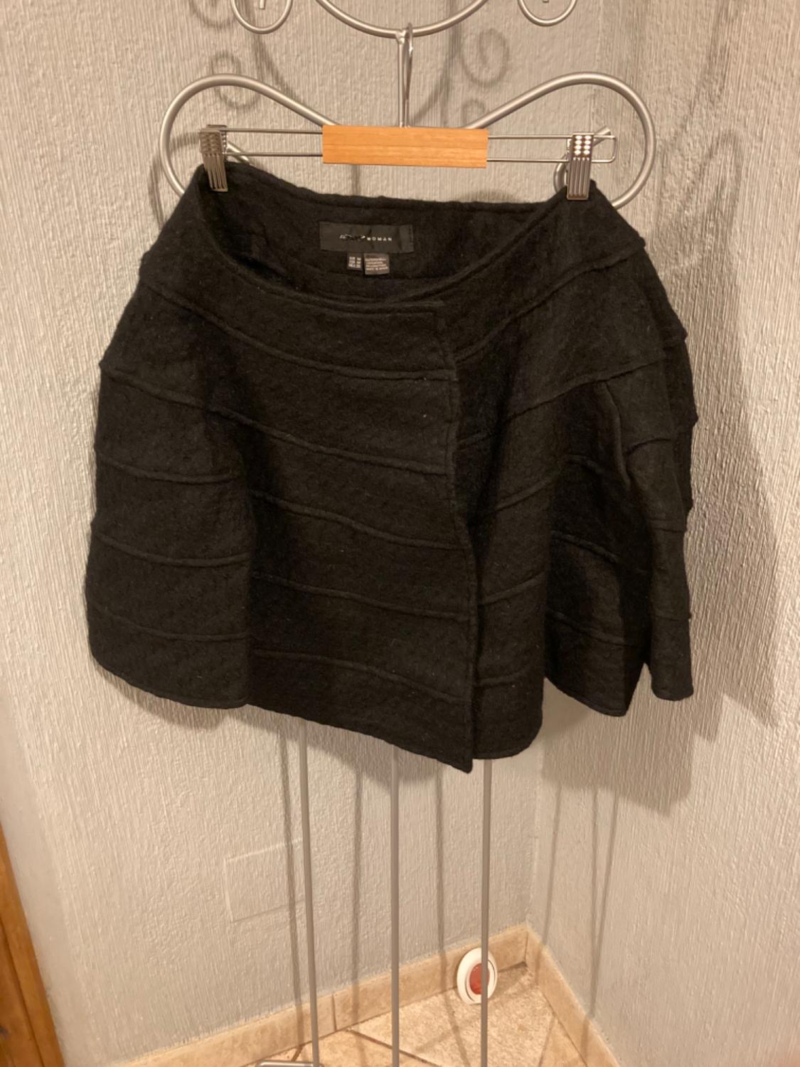 Front view of a black skirt with horizontal pleats and an elasticated waistband.