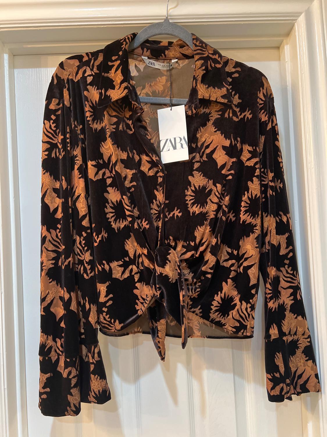 Black velvet blouse with brown floral print, long sleeves and front knot. Visible label with Zara logo.