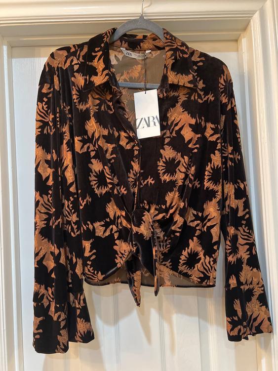Black velvet blouse with brown floral print, long sleeves, and front knot. Visible label with Zara logo.