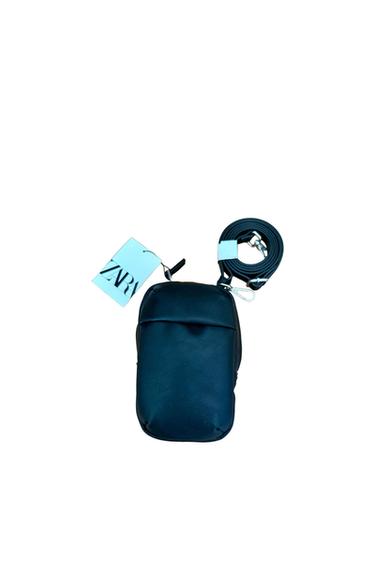 Black handbag with coiled strap and blue label with "ZARA" text on a white background.