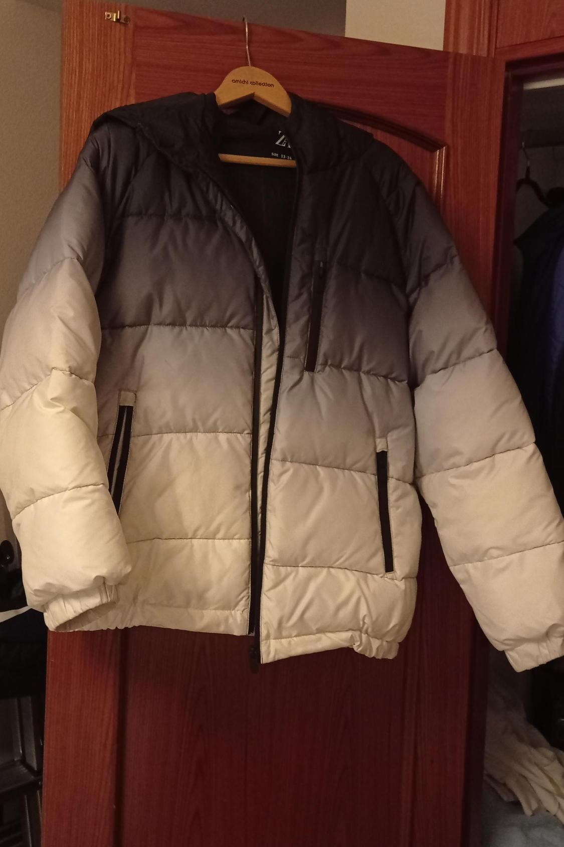 Front view of a quilted jacket in a black and white gradient with side pockets.