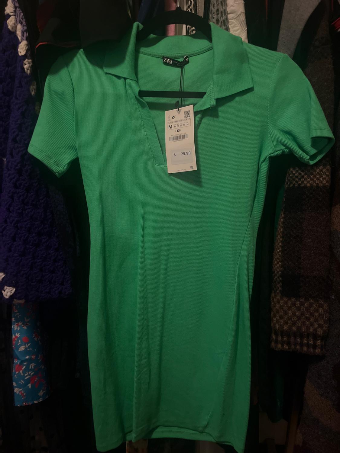 Short green ribbed polo-neck dress hanging in a closet. Tags with the text ZARA, M, $ 25.90.