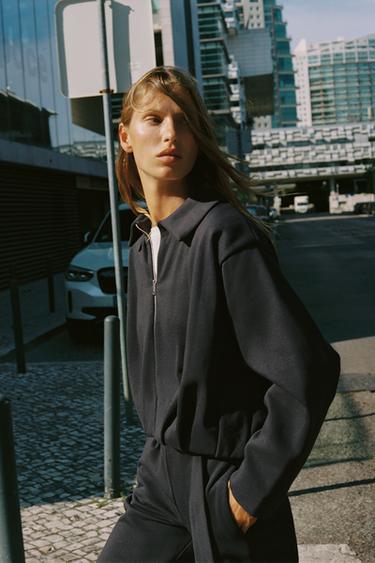 Halbnahe Aufnahme eines schokoladenbraunen Sweatshirts mit Hemdkragen, Frontreißverschluss und langen Ärmeln.