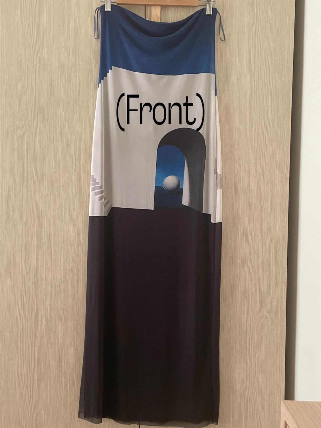 Long dress hanging against a wooden background. Blue, white and black graphic print featuring an arch, a sphere and the text “(Front)”.