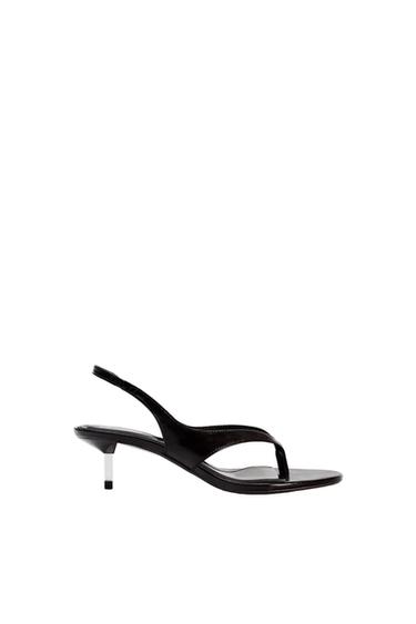 Side view of a black sandal with a thin heel and a heel strap.