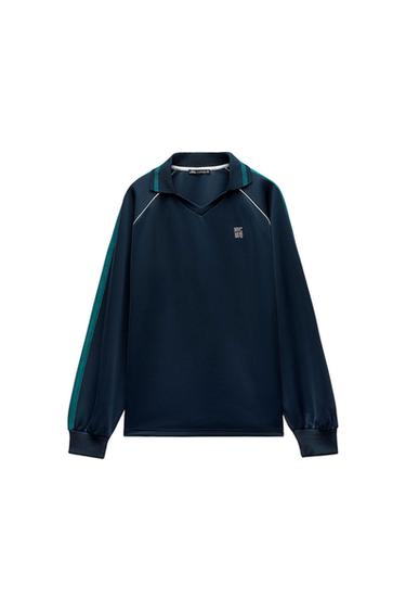 Dark blue long-sleeved polo shirt, V-neck, green stripes, white trim and 'NYC 1970' text on the chest, on a white background.