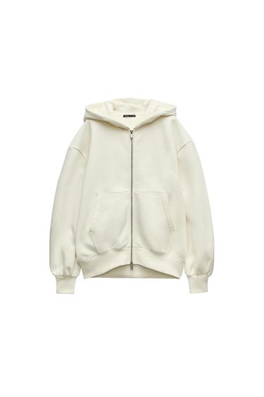 Front view of a cream-coloured zip-up hoodie with front pockets.