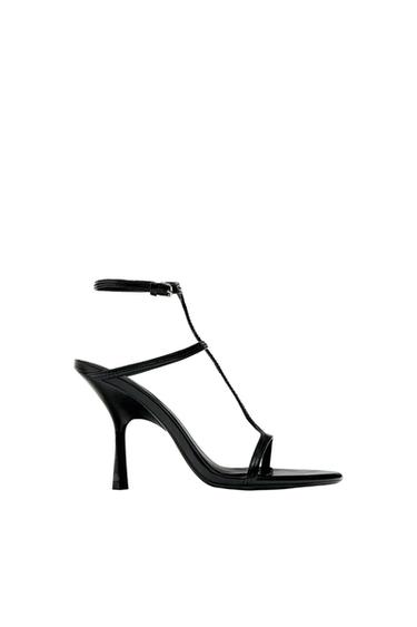 Black high-heeled sandal with thin straps and buckle fastening, on a white background.