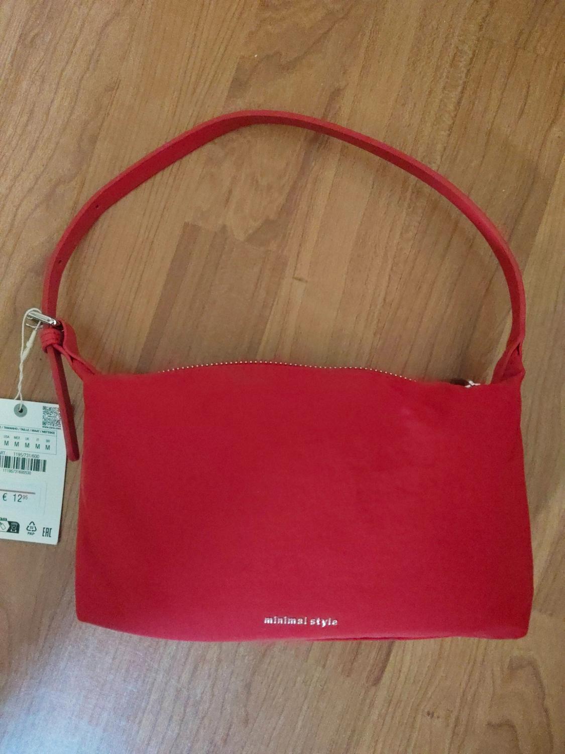 Red handbag with handle on a wooden floor. Includes a label and the text “minimal style” at the bottom.
