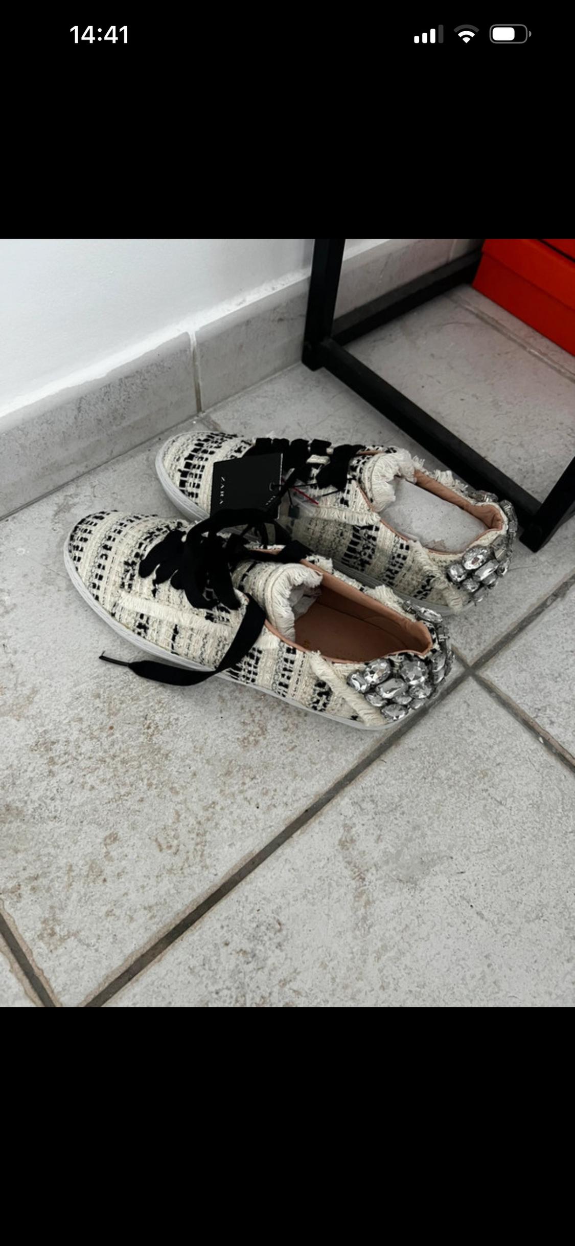 Black and white woven fabric trainers with frayed edges and embellished heels on a tiled floor. Text: 14:41, ZARA.