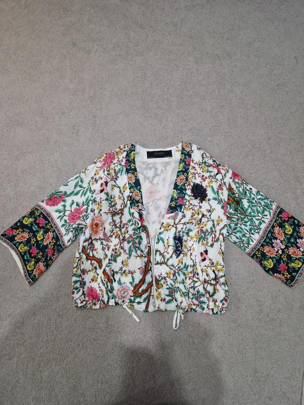 Front view of blouse with multicoloured floral print and wide long sleeves.
