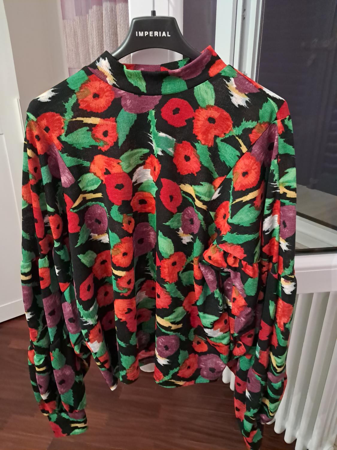 Long-sleeved blouse with a red, green and purple floral print on a black background. Hanging on a hanger with the text IMPERIAL.