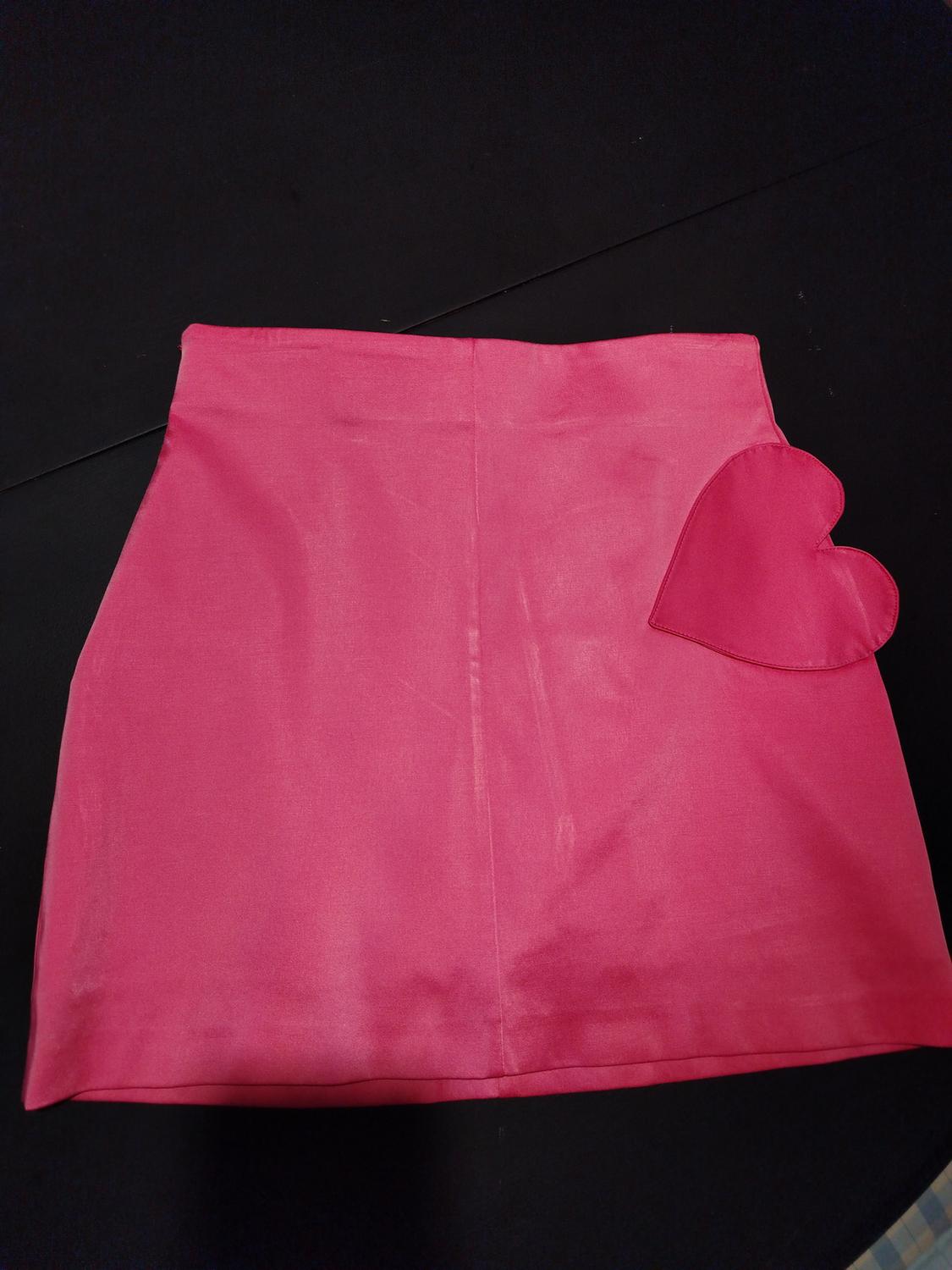 Pink mini skirt with a heart design on the right side, on a black background.