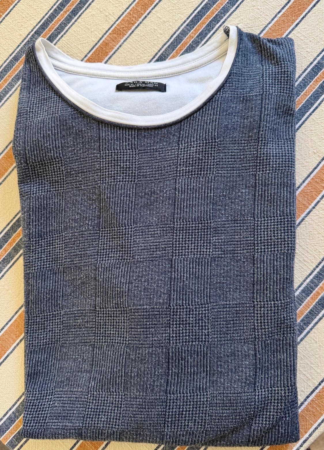 Blue textured plaid shirt with white collar, folded over striped fabric. Text: ZARA MAN EUR XL / USA XL / MEX 44.