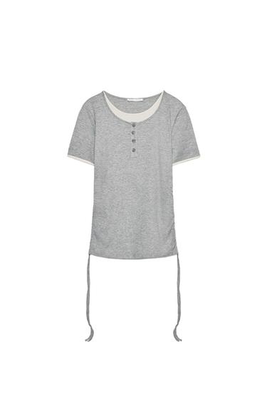 Front view of gray T-shirt with buttons and side ribbons.