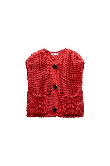 Front view of a chunky red knit waistcoat with large buttons and front pockets.