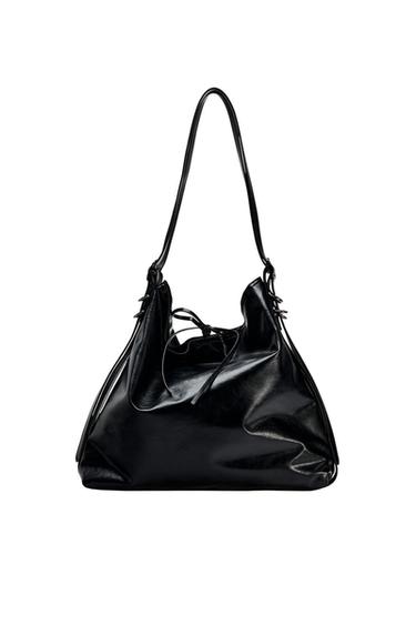 Front view of a black bag with long handles and a drawstring closure.
