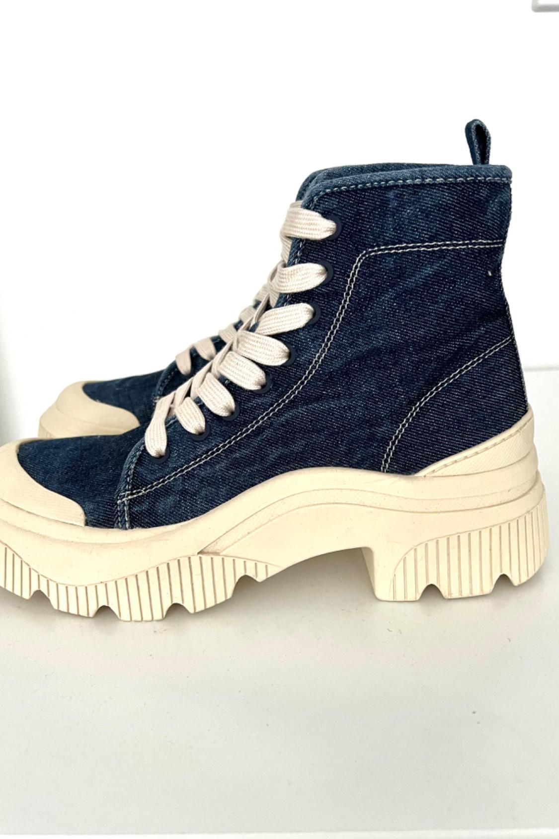 Side view of a blue high-top boot with white laces and a thick beige sole.